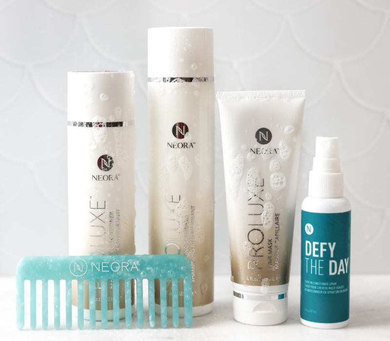 Neora’s Summer Hair Essentials Set, which includes ProLuxe Rebalancing Shampoo and Conditioner, Proluxe Hair Mask and a FREE Ultimate Detangling Comb and Defy the Day Leave-in Conditioner Spray with bubbles on it